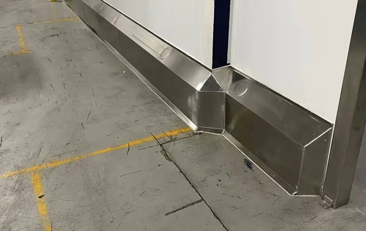 Muret de béton recouvert d'acier inoxydable au bas d'un mur d'usine