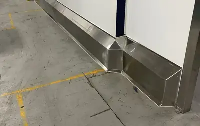 Muret de béton recouvert d'acier inoxydable au bas d'un mur d'usine